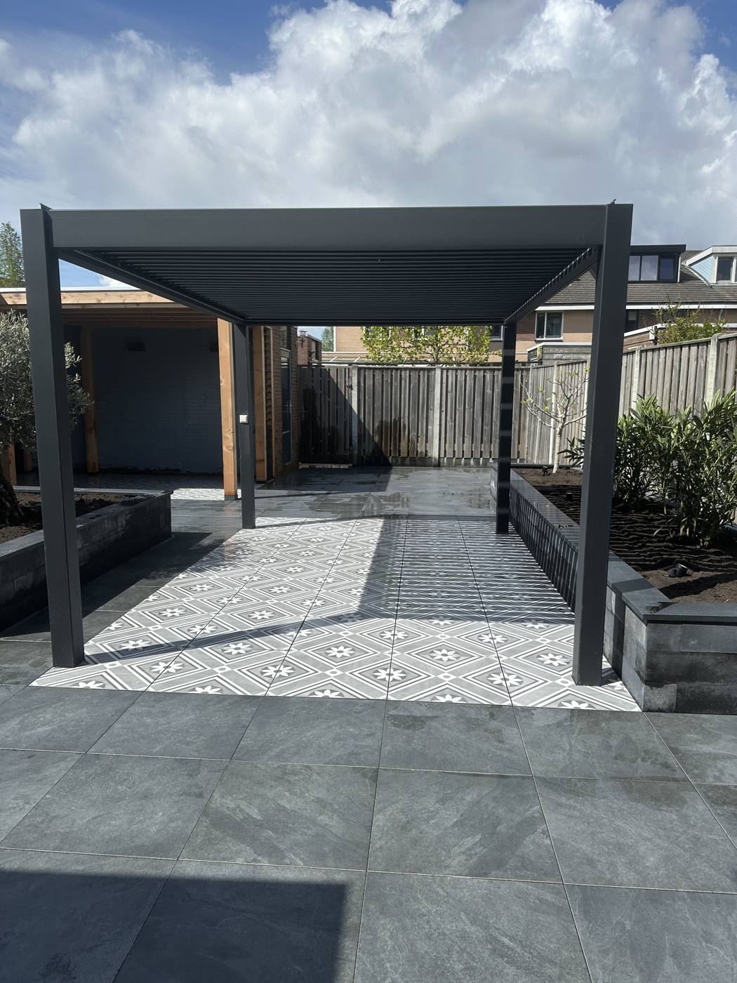 Strakke tuin met pergola en antraciet bestrating