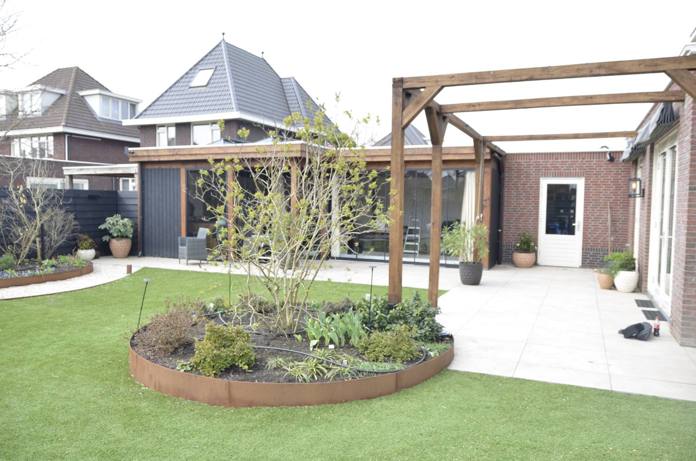 Pergola met border en gazon in de achtertuin