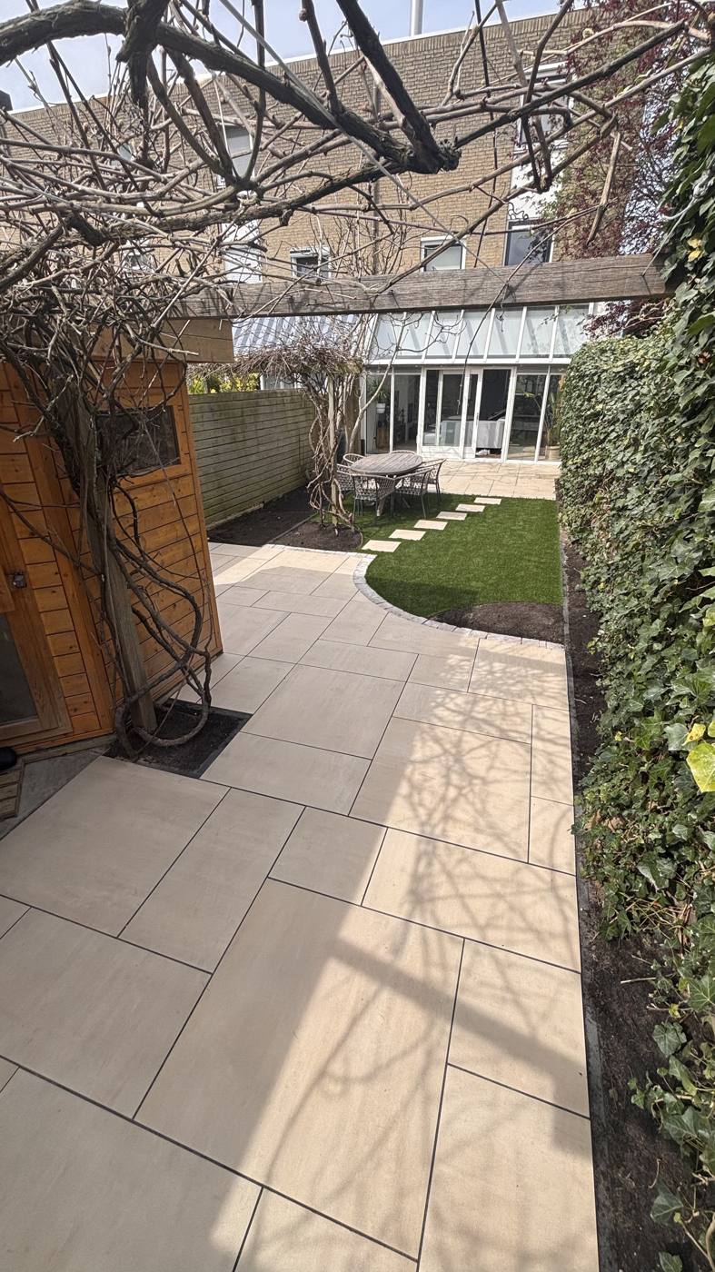 Nieuw bestraat pad langs het gazon, tuinrenovatie Delft